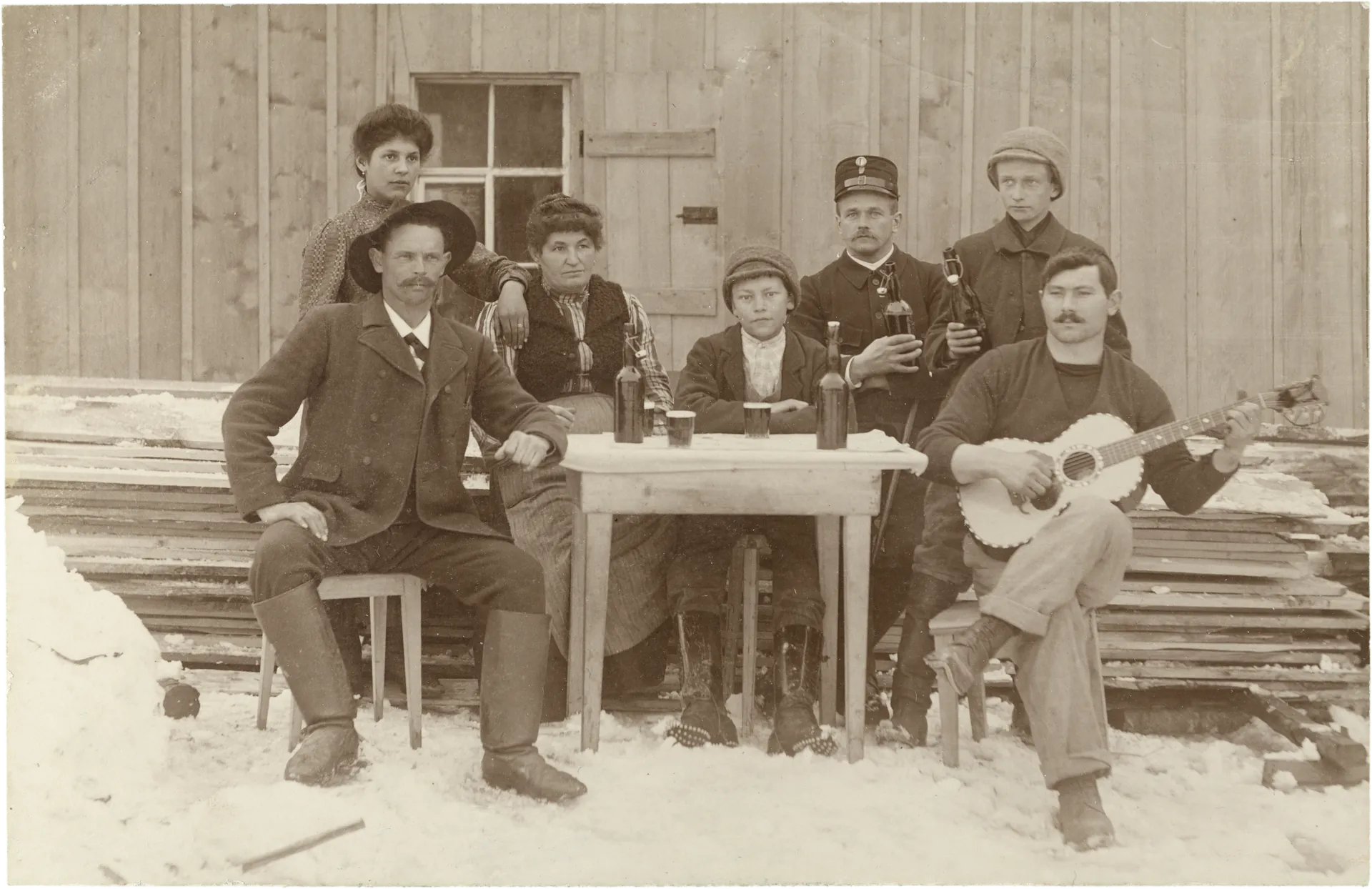 Menschen an Tisch im Schnee, Gitarre und Flaschen – Vorderseite